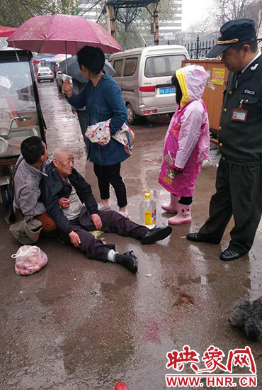 女孩為倒地老人撐傘。