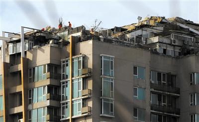 　　昨日，身穿橘黃色馬甲的工作人員在人濟(jì)山莊樓頂拆除違章建筑。新京報(bào)記者 吳江 攝