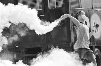 12月2日，泰國(guó)曼谷，一名反政府示威者在總理府附近向負(fù)責(zé)執(zhí)勤的警察投擲催淚彈。英拉請(qǐng)求示威者不要再試圖占領(lǐng)政府工作部門(mén)，不要逼迫政府工作人員選邊站。