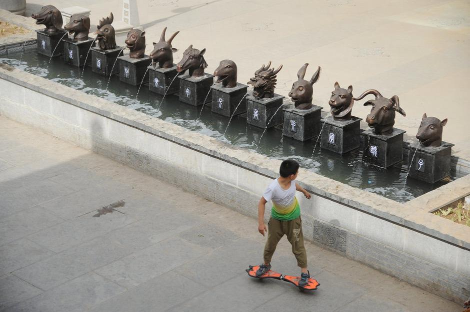 圖為一名市民從獸首旁經(jīng)過(guò)。