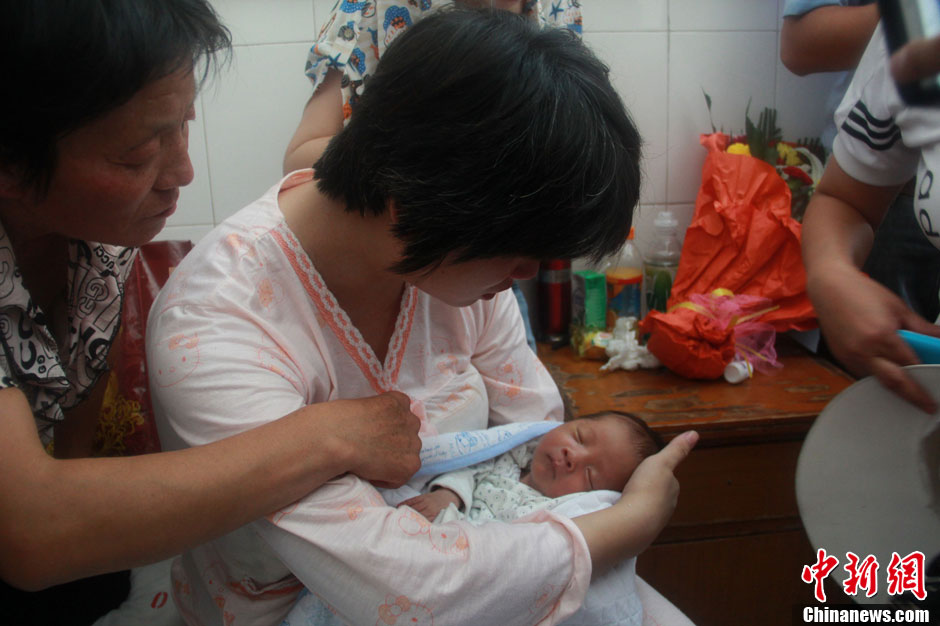 圖為久別重逢，獲救嬰兒母親悉心撫摸愛(ài)子。張一辰 攝