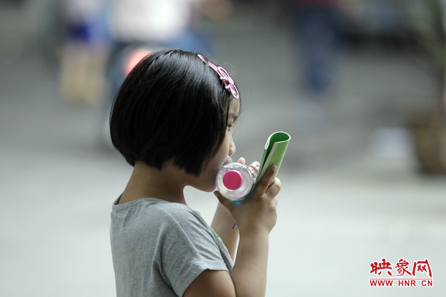 6月7日，鄭州回中考點，一名孩子拿著一瓶礦泉水，等待哥哥走出考場