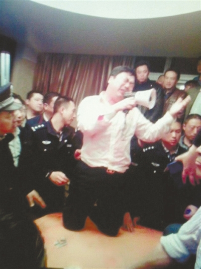 　4月19日，泰州市濱江工業(yè)園區(qū)管委會招待中心，一男子跪在酒桌上喊話求饒。李根 攝