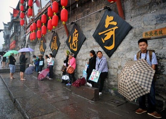 　4月29日上午11時20分，一些游客和古城當(dāng)?shù)氐木用穸阍谝粋€酒吧的屋檐下避雨。這些當(dāng)?shù)鼐用褚詾橛慰团恼罩\生，一場降雨讓他們的生意更加清淡。