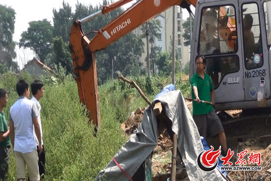 陳寶成手持自制刀斧守在挖掘機旁阻止便衣民警靠前。駕駛室內，張朋珂正向受害人郭曉剛身上澆汽油。（視頻截圖）