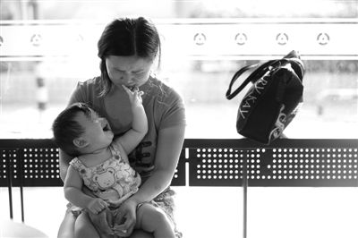 昨日，肯德基京廣中心店門口，姜女士提起跟養(yǎng)父母的關(guān)系時(shí)落淚，懷中9個(gè)月的女兒笑著跟她玩。新京報(bào)記者 薛珺 攝