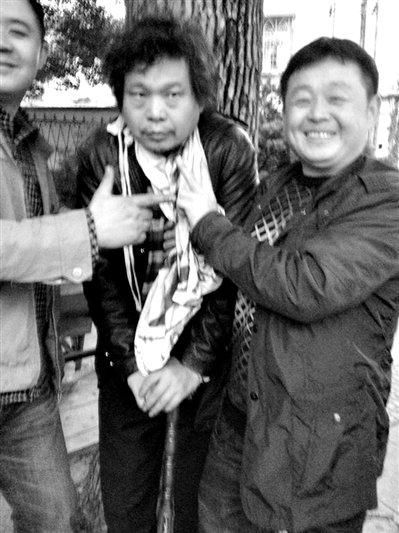 兩名接訪人員與患有癌癥的訪民段新德合影時，面帶笑容擺出勝利的手勢。