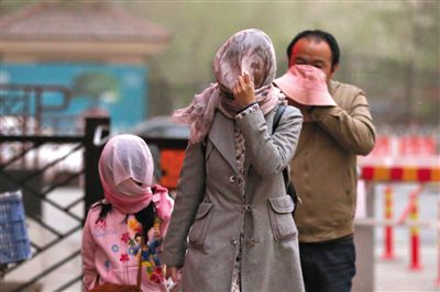 昨日下午，朝陽區(qū)豆各莊，行人將紗巾裹在頭上防沙塵。