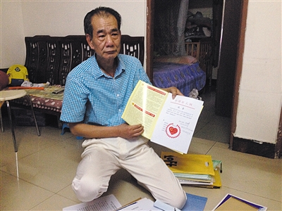 翻出一家網(wǎng)站贈予的“中國好人”證書，區(qū)少坤單膝跪在地上，“你看，我是中國好人啊?！?范春旭 攝