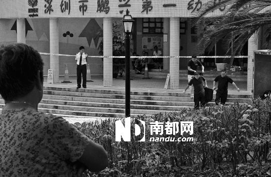 →7月19日，鵬興花園第一幼兒園門前，民警在現(xiàn)場進(jìn)行完勘查取證后，園長和保安的尸體被運(yùn)走。南都記者 徐文閣 攝