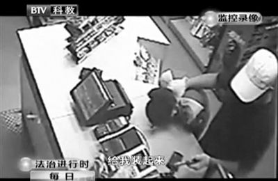 戴帽男子一手掐住加油站營業(yè)員，一手持發(fā)令槍指向另一營業(yè)員，要求“把錢給我裝起來”。