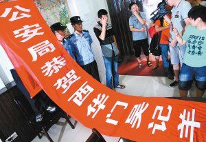 面對(duì)警方收繳的條幅，老板楊某也不好意思地用手遮擋臉