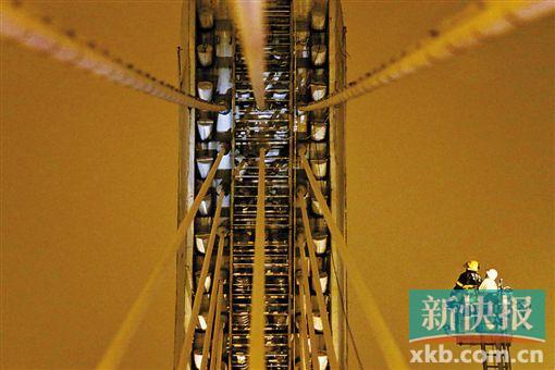 截至今日零時(shí)，男子仍未有下橋舉動(dòng)。圖為公安和消防人員乘消防云梯在高空上和男子交談。