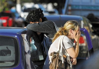 27日，遇難者親友在火災(zāi)現(xiàn)場旁哭泣。