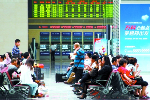 候車大廳溫度很高，一名乘客一手扇風、一手擦汗