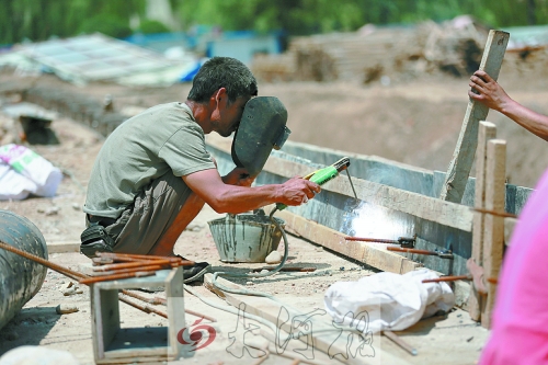 　正午陽(yáng)光下，工地上的焊接工人還在認(rèn)真工作。