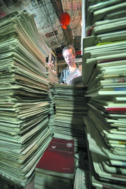 王曉民坐在寫字桌前，被報(bào)紙淹沒。