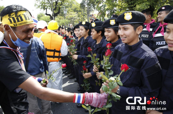 2013年12月03日,曼谷總理府與曼谷警署允許反政府示威民眾進(jìn)入,雙方進(jìn)入暫時(shí)“停戰(zhàn)”狀態(tài)迎接泰王生日。曼谷警察總署,女警們手持鮮花送給反政府示威民眾。圖片來(lái)源:Manish Swarup/東方IC