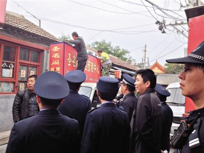 昨日下午,東城區(qū)工商、城管、公安等部門,對雍和宮附近的預測中心進行清理整頓,站在車頂?shù)膬擅と苏鸪患摇邦A測中心”的招牌。因雍和宮、白云觀等文化景點外聚集大量算命先生,被媒體稱為“算命一條街”。本版攝影/新京報記者 李寧 攝