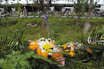 昨日，吉林省德惠市吉林寶源豐禽業(yè)有限公司燃燒事故現(xiàn)場警戒線外，遇難者家屬在路邊擺放了花圈祭奠逝去的親人。吳江 攝