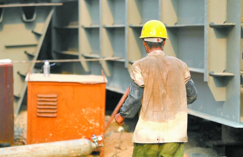 工地上，一建筑工人的衣服被汗水浸透。