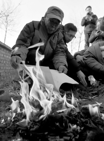 李三仁在兒子墳前焚燒再審無罪判決文書的復印件。新華社發(fā)