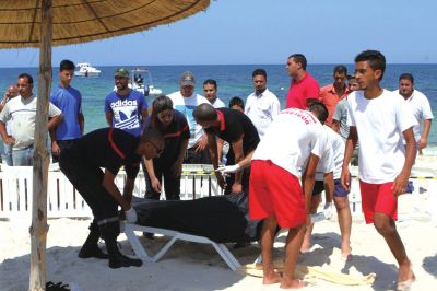 6月26日，在突尼斯蘇塞，救生員和醫(yī)務(wù)人員在發(fā)生襲擊事件的海灘運(yùn)送一名死者的遺體。新華社發(fā)