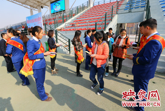 活動現(xiàn)場工作人員給同學(xué)們發(fā)放宣傳冊、環(huán)保袋。