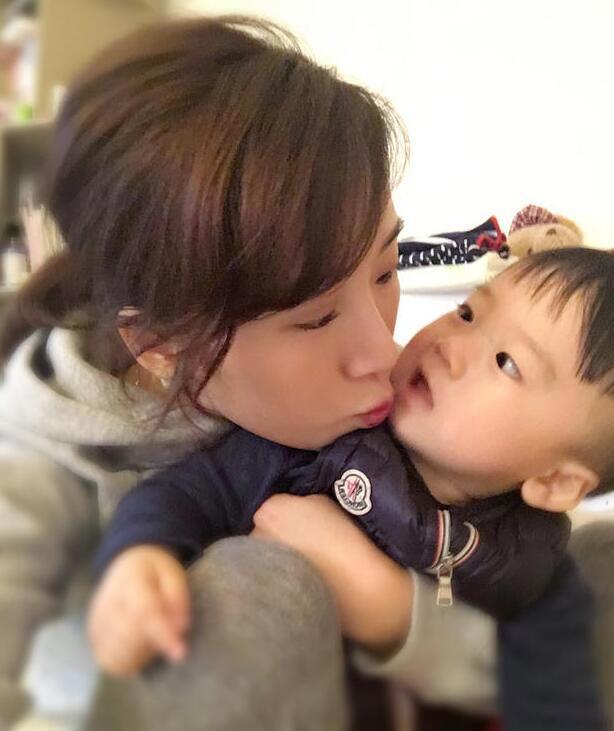 照片中李念狂吻兒子，小寶貝自顧自地玩著。