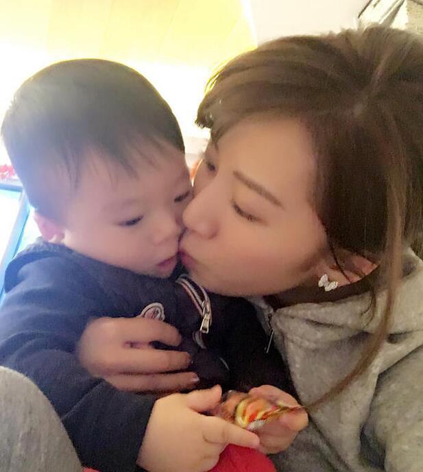 照片中李念狂吻兒子，小寶貝自顧自地玩著。