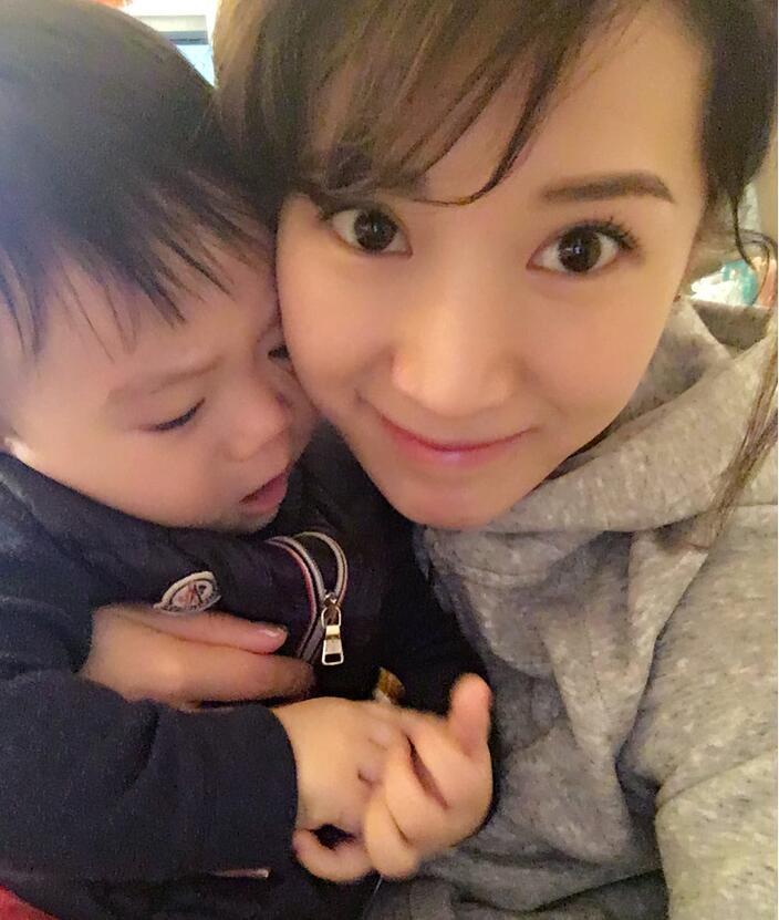 照片中李念狂吻兒子，小寶貝自顧自地玩著。