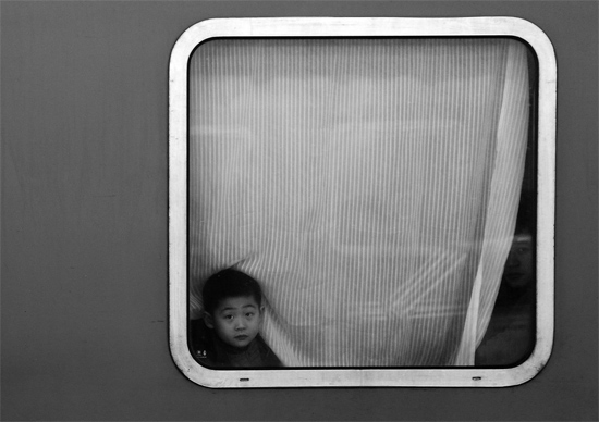 一個孩子把頭伸向窗外，他想再看送別的親人一眼