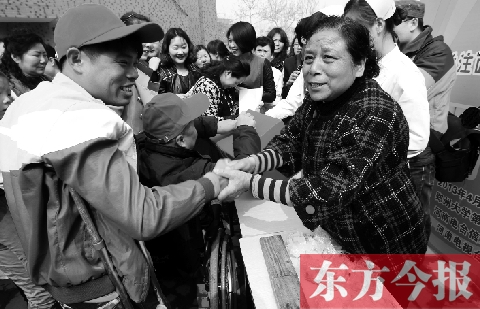 昨日，鄭大四附院的大樓前，“面人鄭”鄭玉芬（右）向前來捐款的殘疾人表示感謝