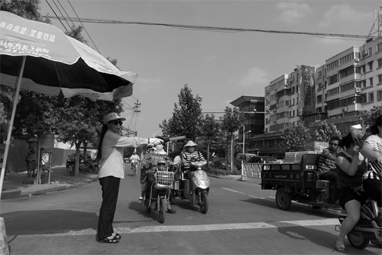 昨日，開封市區(qū)一名協(xié)管員在指揮群眾過馬路