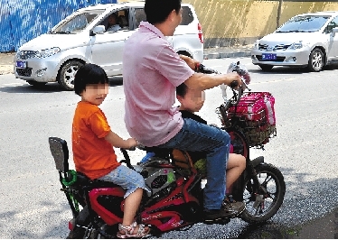 周先生騎著一輛低矮的電動(dòng)車帶著一對兒女，很不安全。