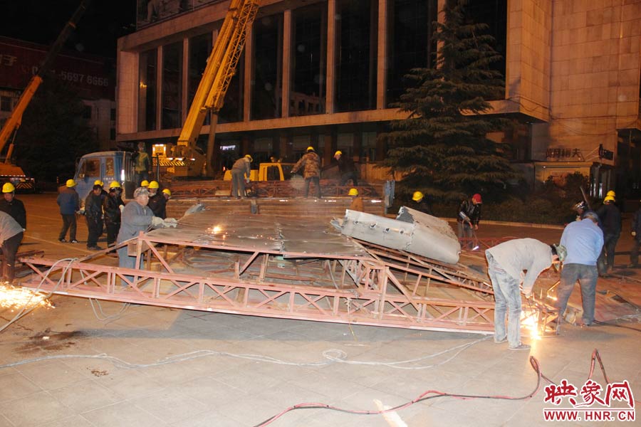 地面上的20多名工人對(duì)吊裝下的廣告牌進(jìn)行分割。