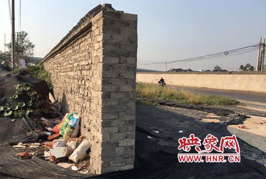 一墻之隔，一邊是道路，一邊是垃圾和荒草，市民質(zhì)疑其為遮羞墻。