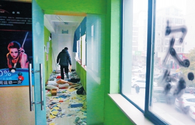 　健身會(huì)所地上一片狼藉，玻璃上噴著黑色“欠錢”二字。