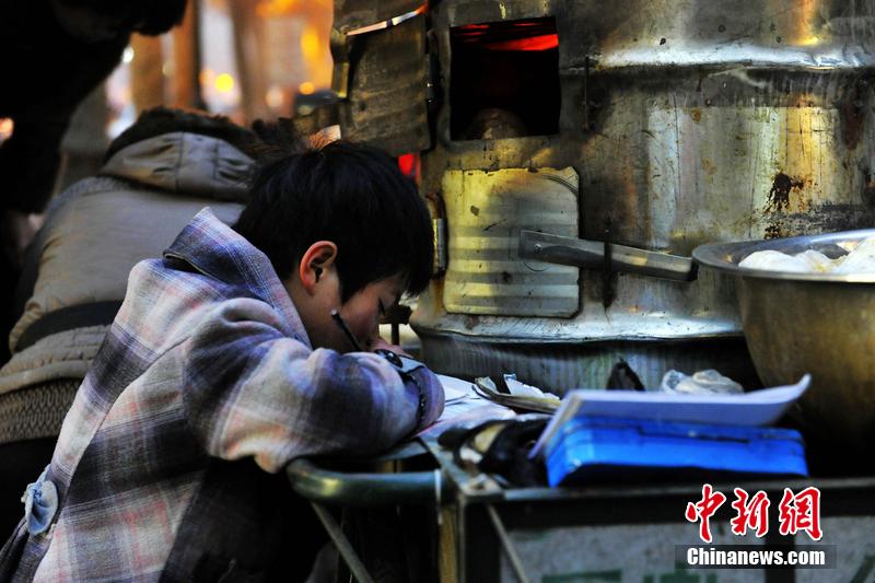 男孩西安路燈下寫(xiě)作業(yè) 媽媽邊賣(mài)紅薯邊輔導(dǎo)