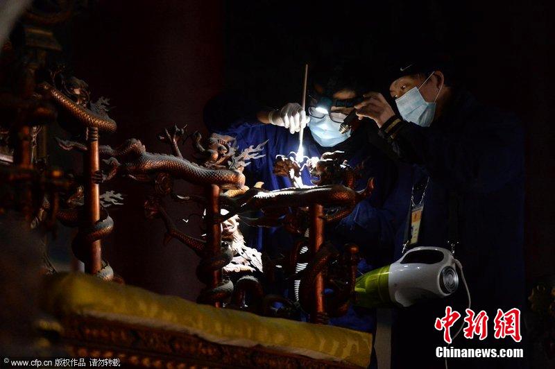圖為工作人員使用軟毛刷和吸塵器對太和殿的金漆雕龍寶座除塵。