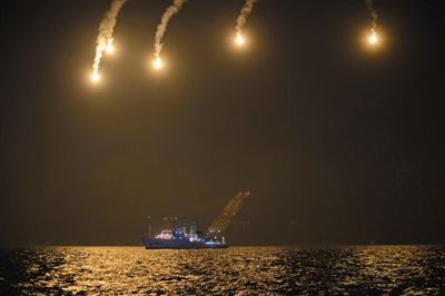 22日，搜救人員在照明彈的光亮下連夜搜救。