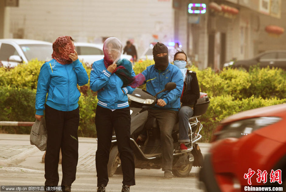 2014年04月23日，新疆維吾爾自治區(qū)吐魯番地區(qū)，市民戴著口罩行走在大風(fēng)沙塵中的吐魯番市街頭。