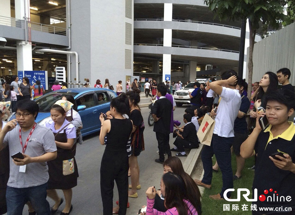 當(dāng)?shù)貢r間2014年5月5日，泰國清萊，工人們站在一棟大樓外避難。