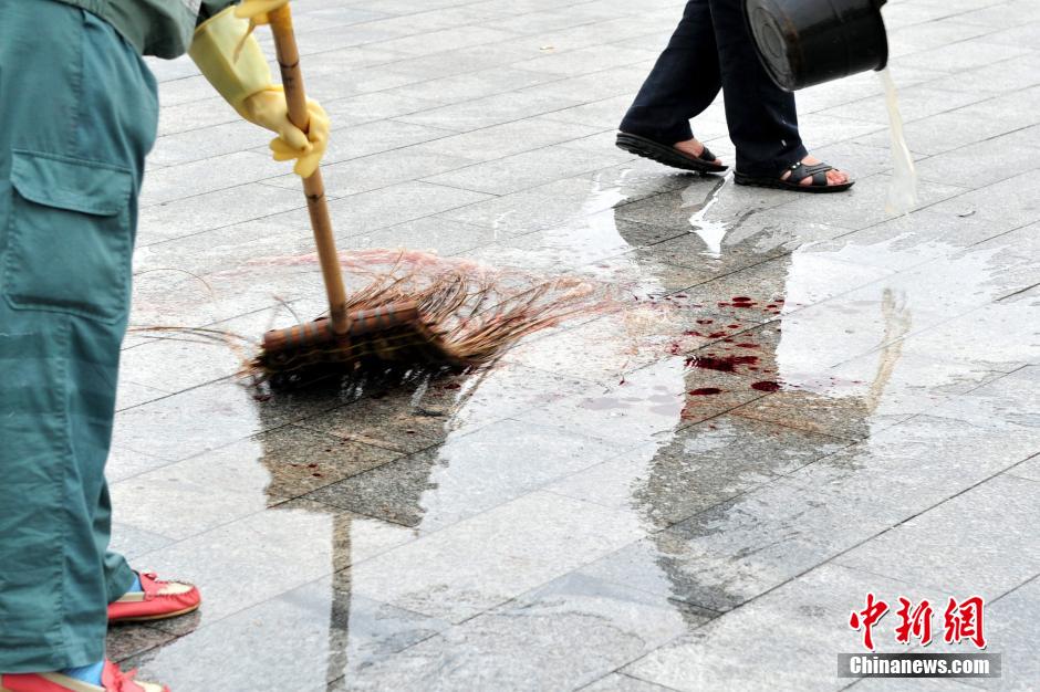 圖為環(huán)衛(wèi)工人在清理案發(fā)地點(diǎn)的血跡。