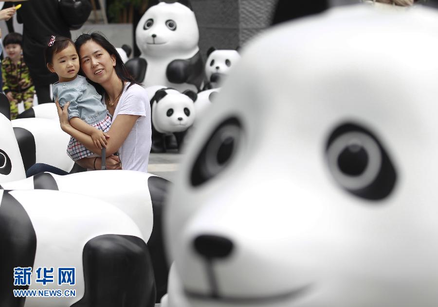 6月2日，一位家長帶著孩子在上海街頭和大熊貓模型合影。