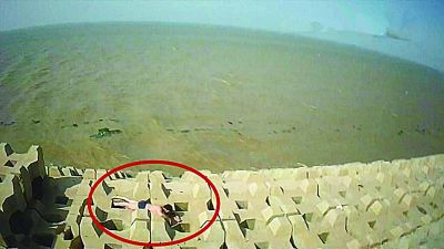 孫正龍游上岸，趴在海邊精疲力盡。