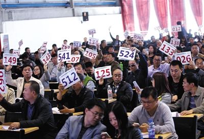 競(jìng)拍者正在練習(xí)舉牌動(dòng)作，以便拍賣時(shí)讓工作人員看清號(hào)牌。