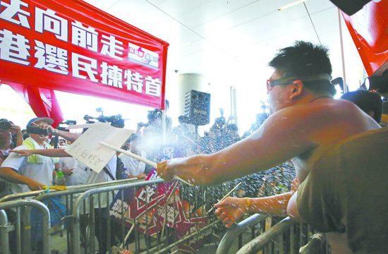 17日，在香港立法會外，一名反對政改的男子向支持派人群投擲標(biāo)牌。