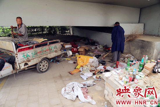 負(fù)責(zé)高架橋下綠化的人員在清理流浪漢留下的垃圾和雜物。