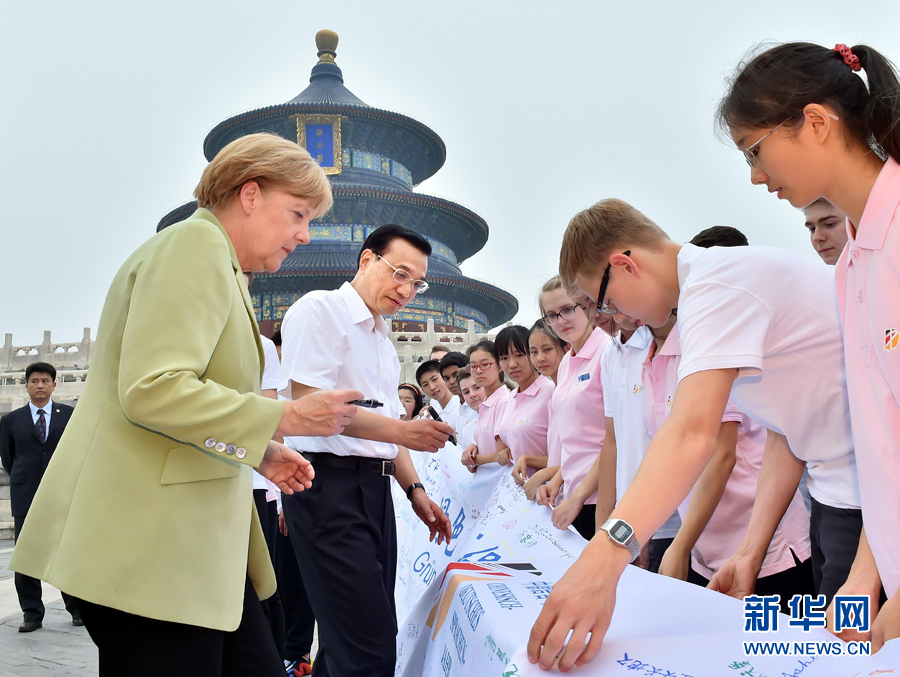 李克強(qiáng)同默克爾在紀(jì)念橫幅上簽名。